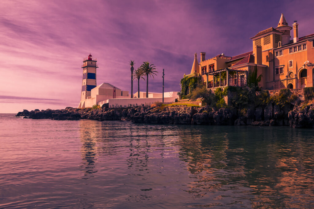 Beautiful sunset on the coast of Cascais, Portugal with a lighthouse and purple skies.